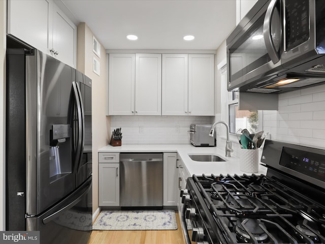 kitchen with stainless steel appliances, light hardwood / wood-style floors, and white cabinets