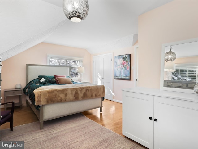 bedroom with multiple windows, lofted ceiling, and light hardwood / wood-style floors