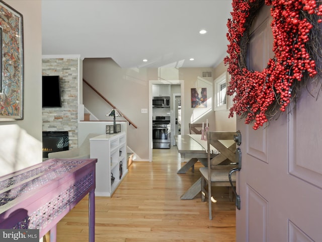 foyer entrance with a fireplace and light wood-type flooring