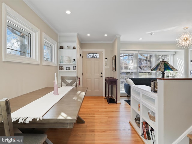 dining area with a notable chandelier, crown molding, and light wood-type flooring