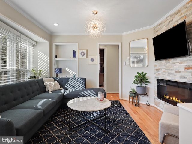 living room featuring hardwood / wood-style flooring, crown molding, a stone fireplace, and a chandelier