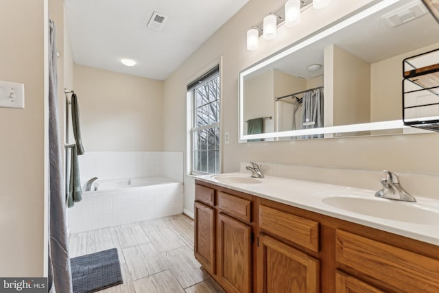 bathroom with tiled tub and vanity