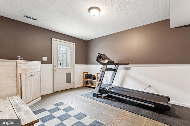 exercise room featuring light tile patterned floors and a textured ceiling