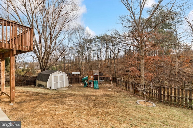 view of yard featuring a playground, a wooden deck, and a storage shed