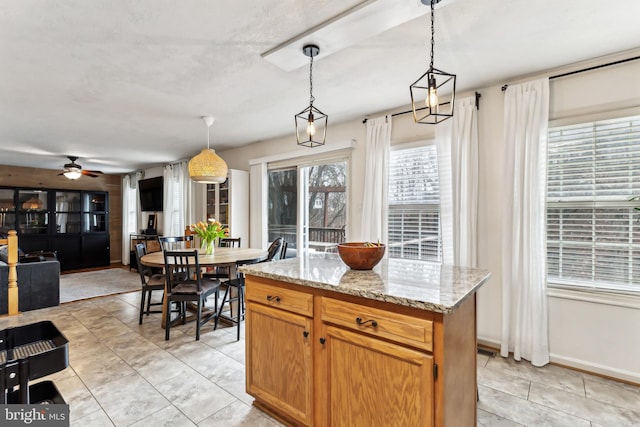 kitchen with light stone counters, decorative light fixtures, a center island, and light tile patterned flooring