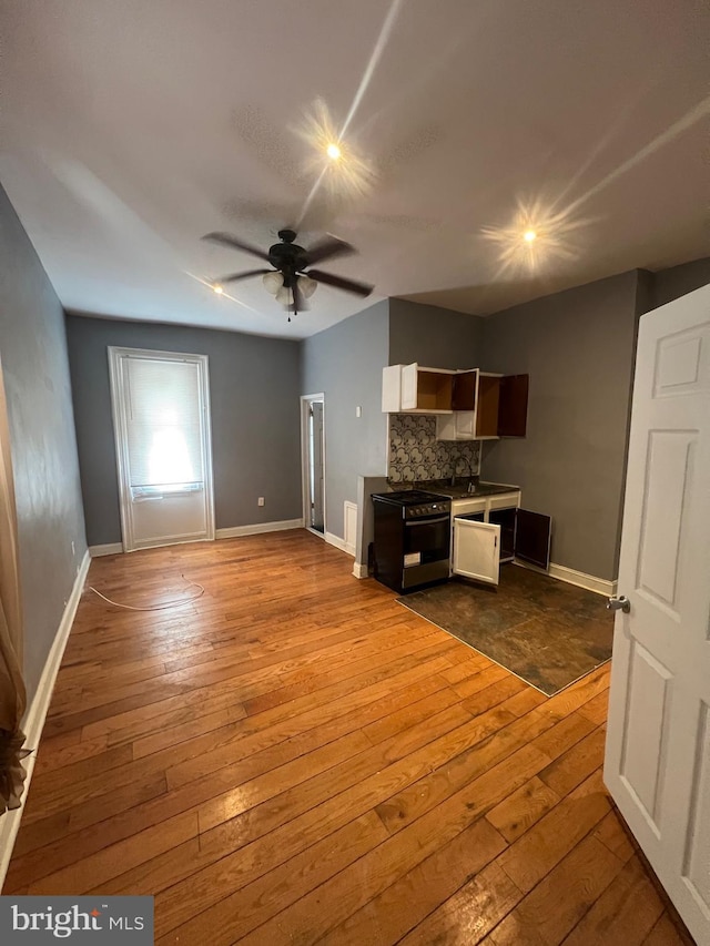 kitchen featuring dark wood-type flooring, electric range, ceiling fan, and decorative backsplash