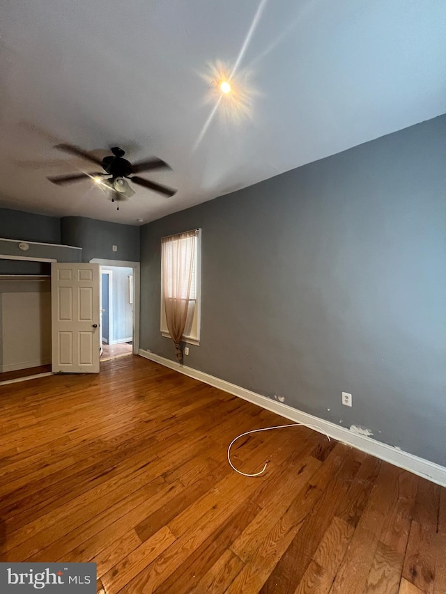 unfurnished bedroom with wood-type flooring, a closet, and ceiling fan