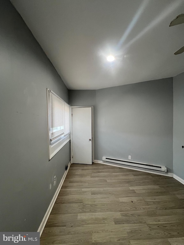 unfurnished room featuring wood-type flooring and baseboard heating