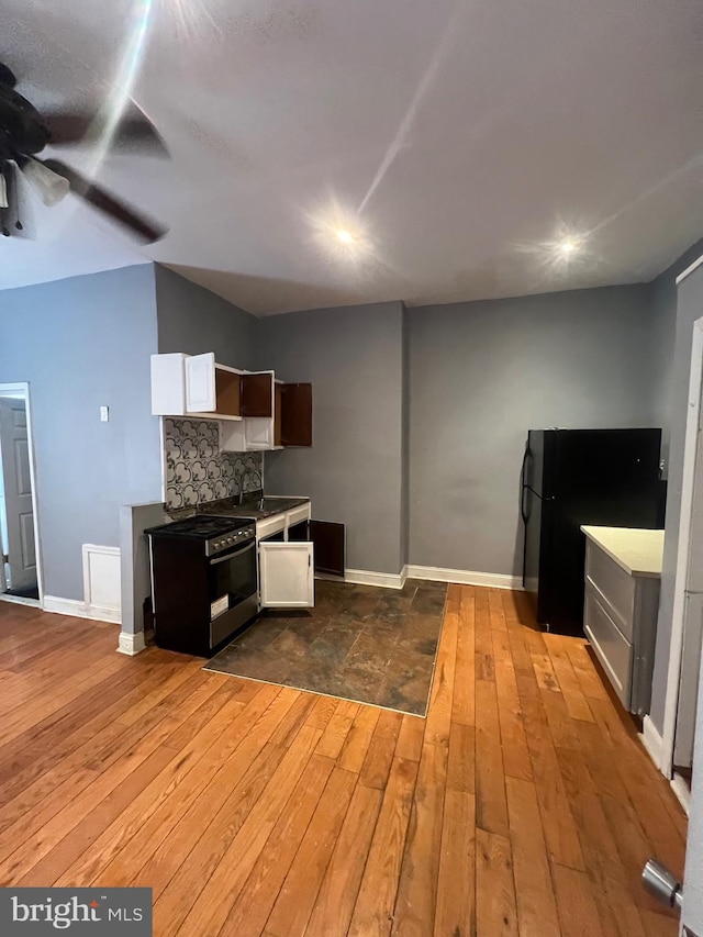 kitchen featuring white cabinetry, black refrigerator, backsplash, and dark hardwood / wood-style flooring