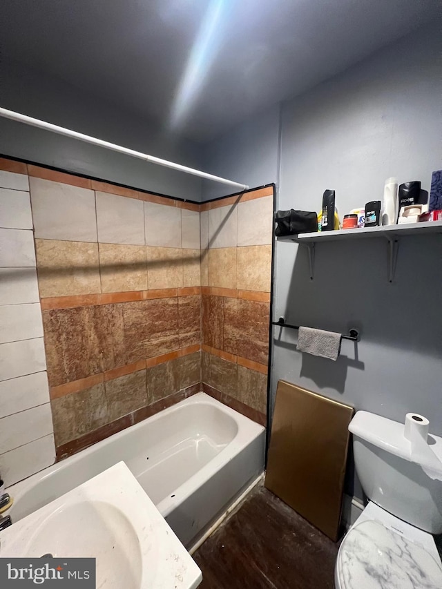 full bathroom with hardwood / wood-style floors, tiled shower / bath, sink, and toilet