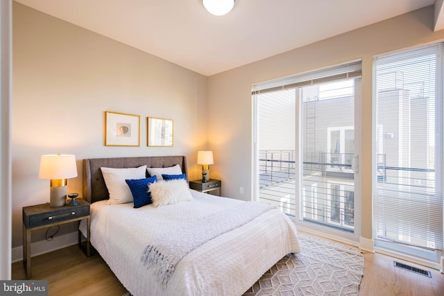 bedroom with access to exterior and wood-type flooring