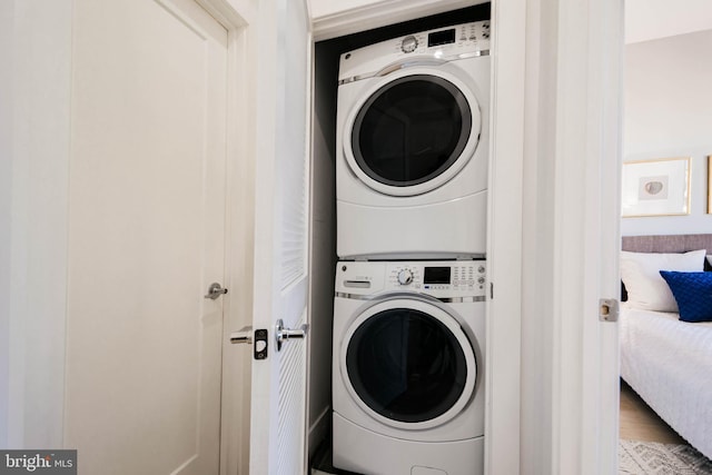 washroom with stacked washer / dryer and wood-type flooring