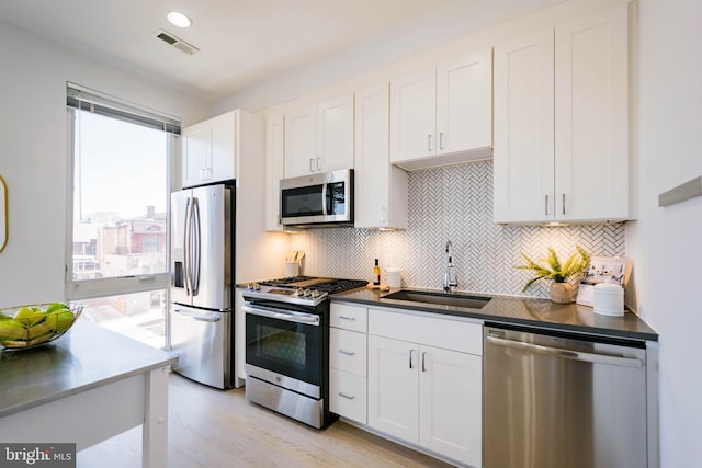 kitchen with white cabinetry, appliances with stainless steel finishes, sink, and tasteful backsplash