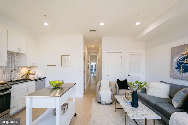 kitchen with white cabinetry, stainless steel appliances, sink, and decorative backsplash