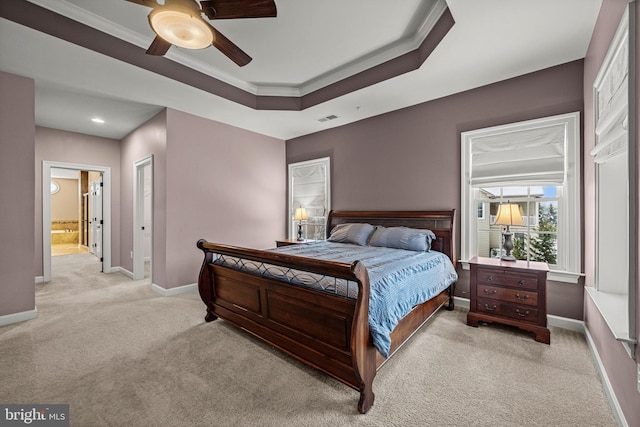 carpeted bedroom featuring a raised ceiling, ornamental molding, connected bathroom, and ceiling fan