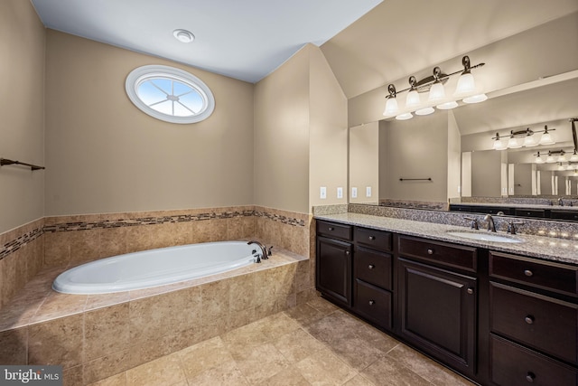 bathroom with tiled tub and vanity