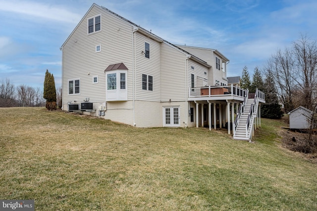 back of house featuring central AC unit, a deck, and a lawn