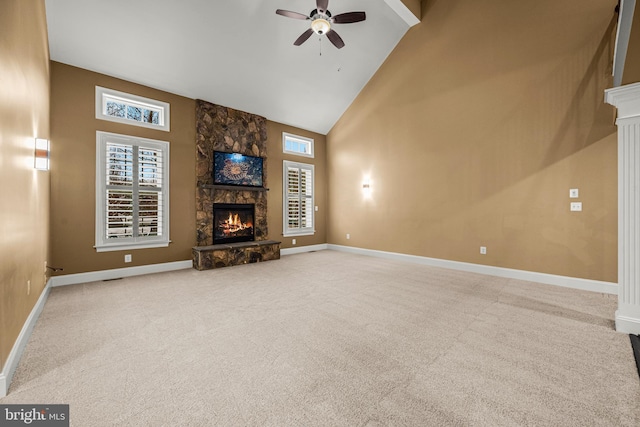 unfurnished living room with ceiling fan, a stone fireplace, carpet, and high vaulted ceiling