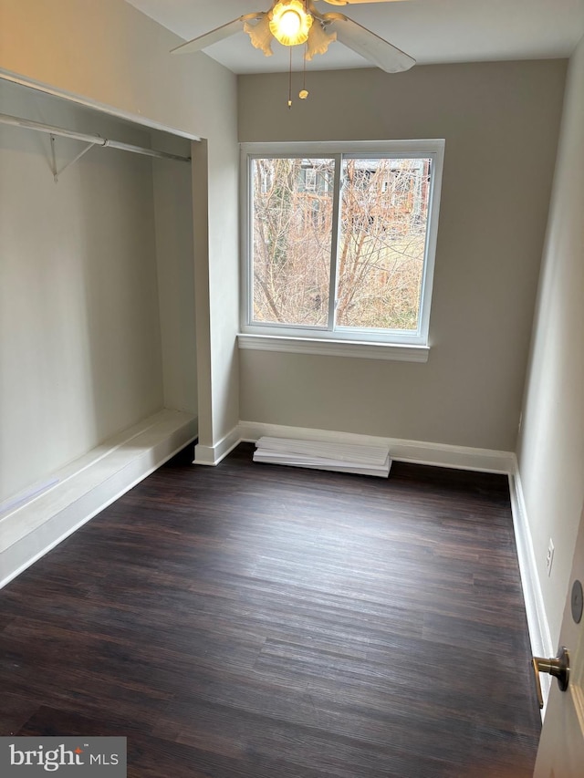 unfurnished bedroom with dark wood finished floors, a ceiling fan, and baseboards