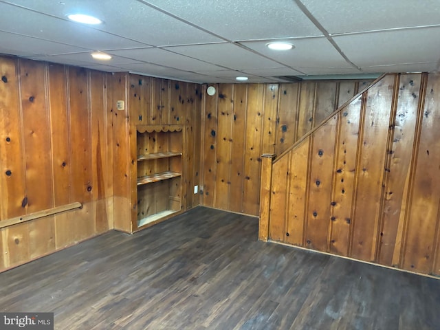 finished basement featuring wood walls, wood finished floors, and a paneled ceiling