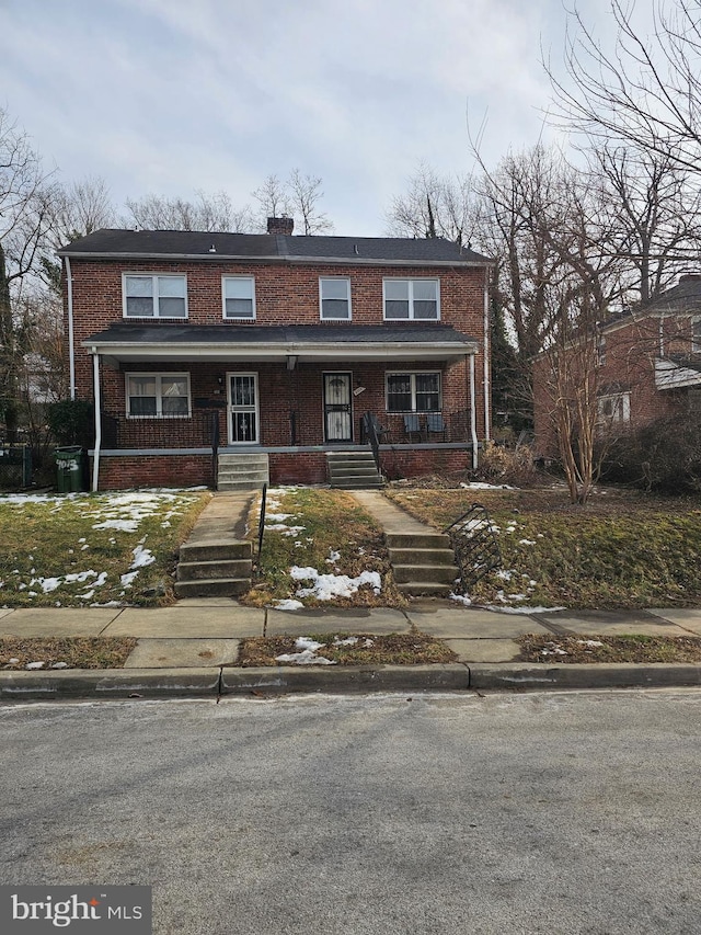 multi unit property with a porch and brick siding