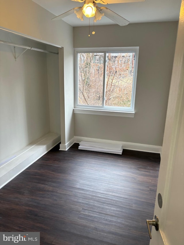 unfurnished bedroom featuring ceiling fan, dark wood-type flooring, a closet, and baseboards