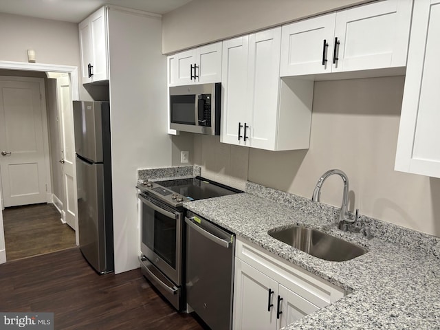 kitchen featuring dark wood-style flooring, a sink, white cabinetry, appliances with stainless steel finishes, and light stone countertops