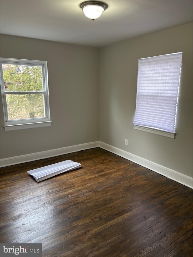 spare room with dark wood-style floors and baseboards