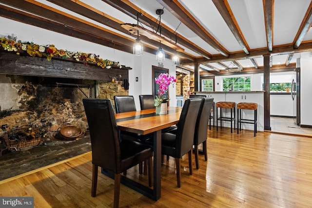 dining area featuring beamed ceiling and light wood-type flooring