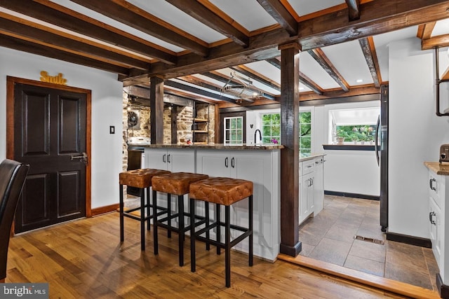 kitchen with white cabinetry, beam ceiling, and a kitchen island