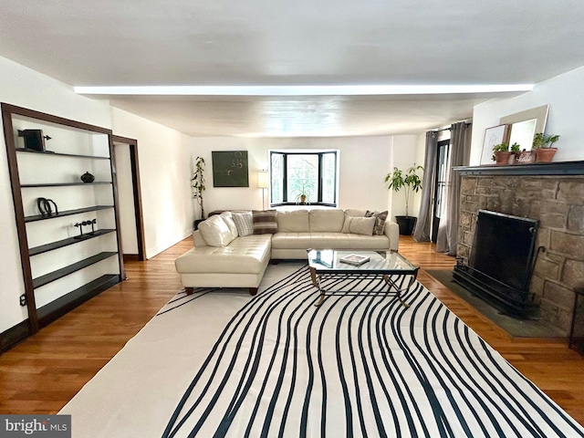 living room with a stone fireplace and dark hardwood / wood-style floors