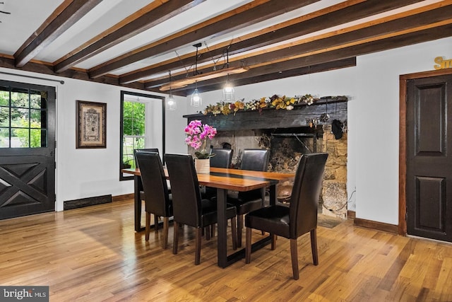 dining room featuring beam ceiling, a wealth of natural light, and light wood-type flooring