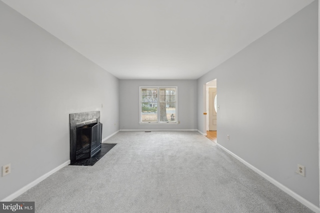 unfurnished living room with carpet, a premium fireplace, and baseboards