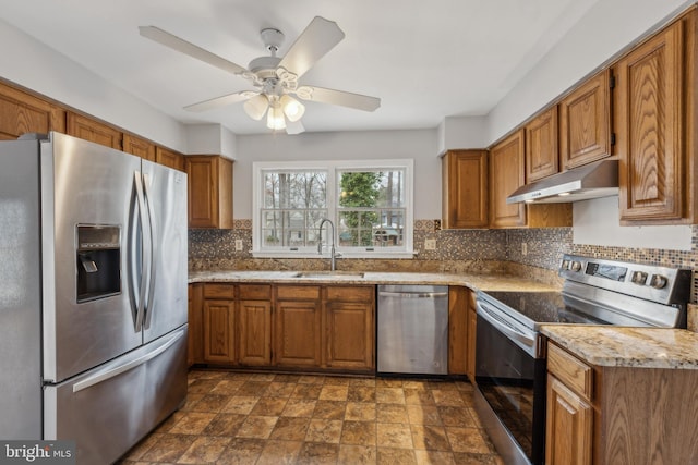 kitchen with stainless steel appliances, brown cabinets, a sink, and under cabinet range hood