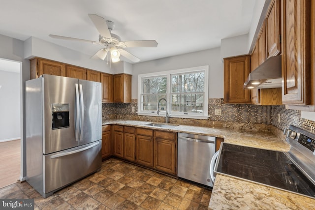 kitchen with decorative backsplash, brown cabinets, range hood, stainless steel appliances, and a sink