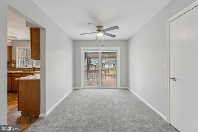 empty room with carpet, a sink, baseboards, and ceiling fan