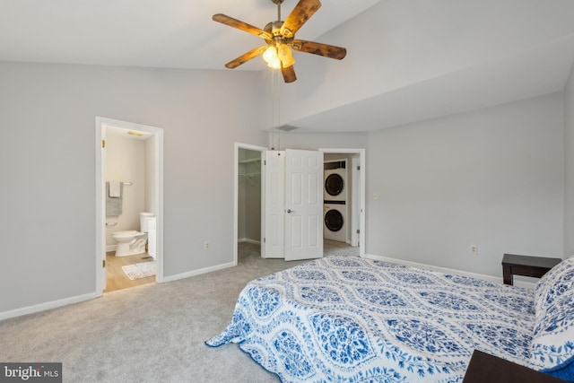 bedroom featuring carpet floors, baseboards, vaulted ceiling, a walk in closet, and stacked washer and clothes dryer