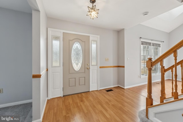 entryway with stairs, light wood finished floors, visible vents, and baseboards