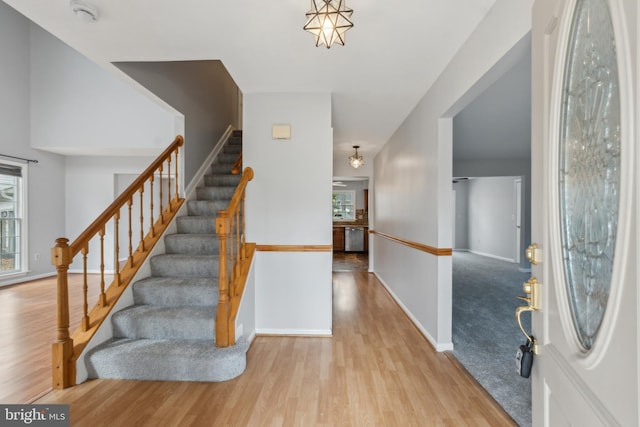 foyer entrance featuring light wood-style flooring, stairs, and baseboards