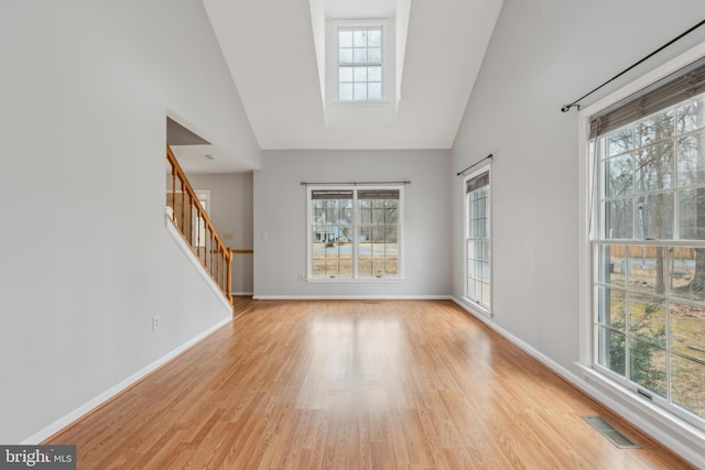 unfurnished living room with light wood-style floors, a healthy amount of sunlight, visible vents, and baseboards