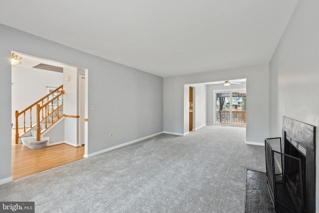 unfurnished living room featuring carpet floors, stairs, baseboards, and a fireplace