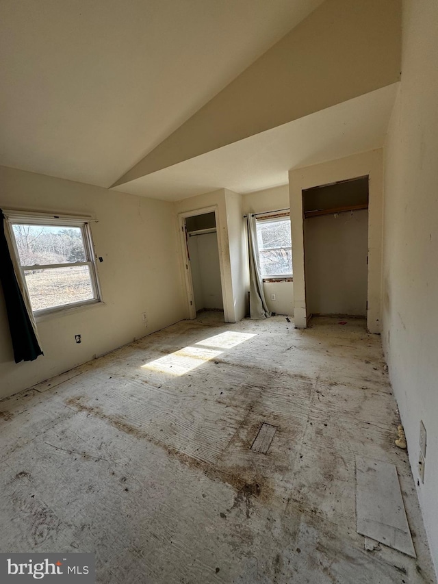 unfurnished bedroom featuring multiple closets and lofted ceiling