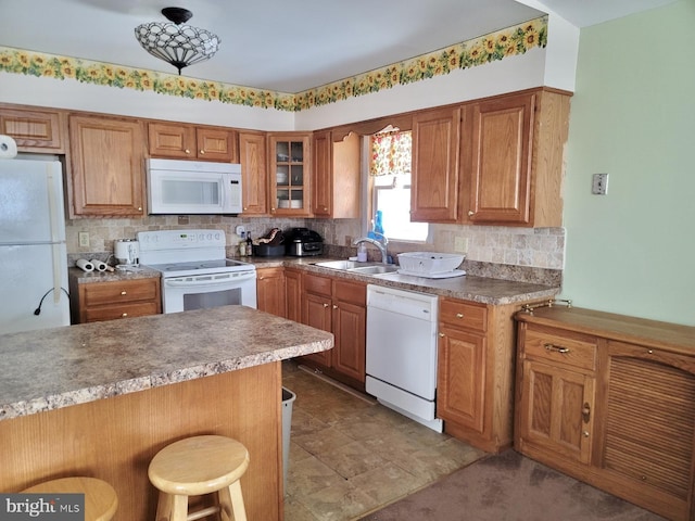 kitchen with sink, white appliances, a kitchen breakfast bar, tasteful backsplash, and kitchen peninsula