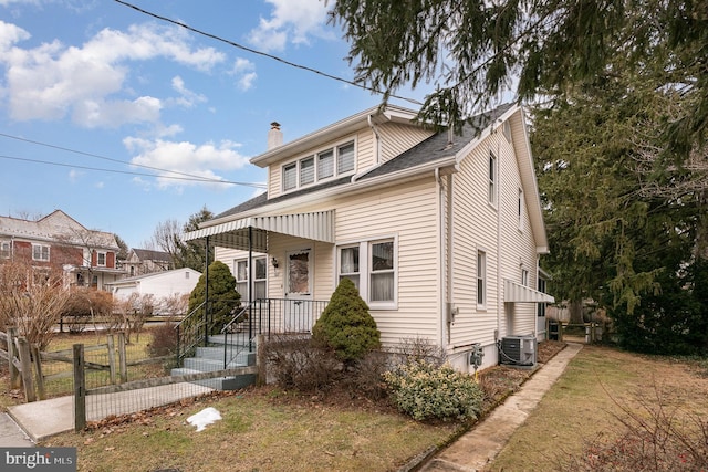 bungalow-style house with cooling unit and a front lawn