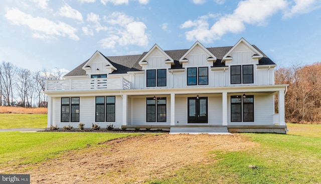 view of front of house with a balcony, a front yard, and french doors