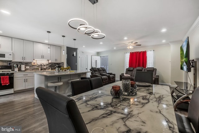 dining space with sink, ornamental molding, and ceiling fan