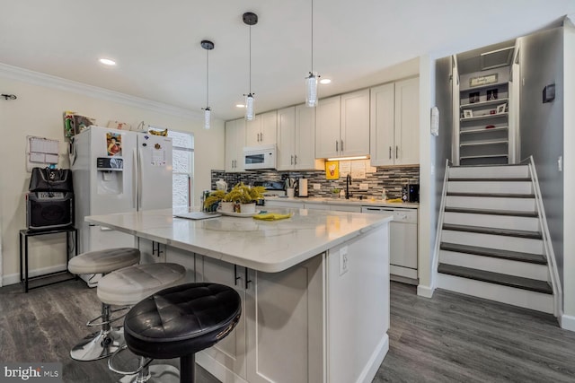 kitchen with white cabinetry, light stone counters, white appliances, and a center island