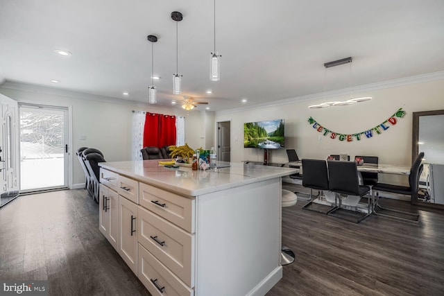 kitchen with white cabinetry, decorative light fixtures, a center island, and light stone counters