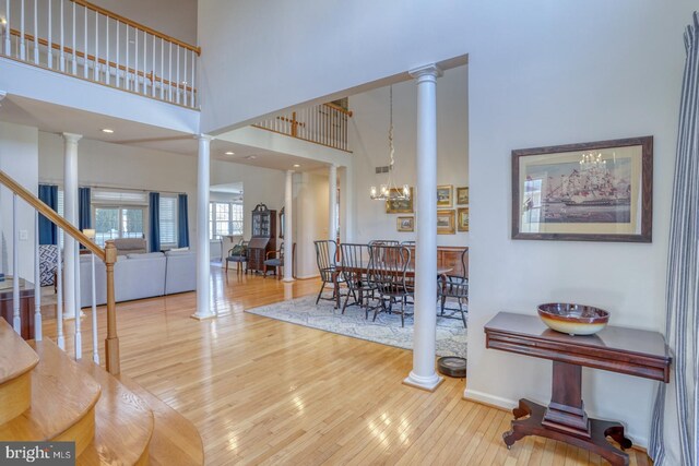 foyer entrance featuring ornate columns, hardwood / wood-style floors, and a chandelier