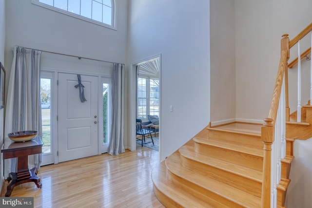 foyer entrance with a towering ceiling and light hardwood / wood-style flooring